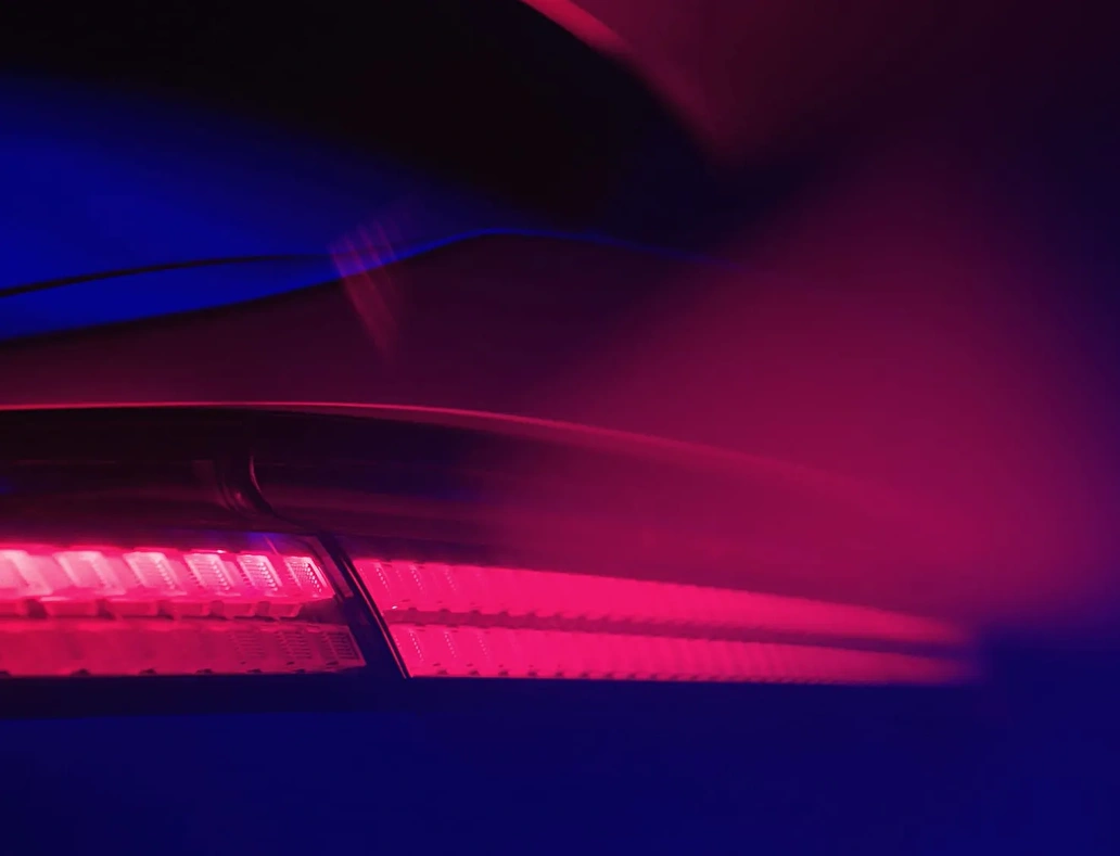 Primer plano de la luz trasera LED roja de un coche Hyundai, reflejando la estética futurista de la identidad visual del evento corporativo.